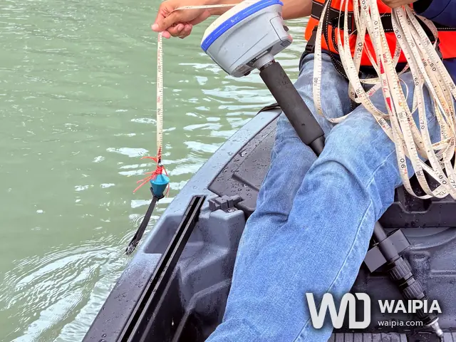 หย่อนลูกดิ่งผูกสายวัดลงสู่ท้องบ่อ ข้างเครื่องรับ GNSS บนเรือ