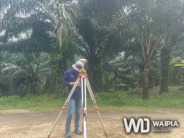 ช่างสำรวจตั้งเครื่องรับ GNSS บนขาตั้งที่หมุดบนถนนคอนกรีต